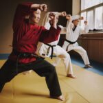 Sensei and two martial arts students with black belts training together.
