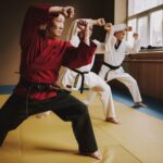 Sensei and two martial arts students with black belts training together.