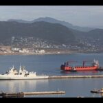 Lady R (vessel with the red hull, right) being tugged away from Naval Base Simon's Town on 9 December 2022, the SAS Mendi (left) can be seen in the foreground.