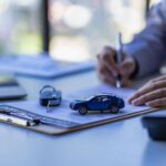 Car sales concept, sales reps give keys to customers on table with small car samples and office insurance.