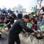 Palestinians collect food at a donation point in a refugee camp in Rafah in the southern Gaza Strip on December 23, 2023, amid continuing battles between Israel and the militant group Hamas. (Photo by Mahmud HAMS / AFP)