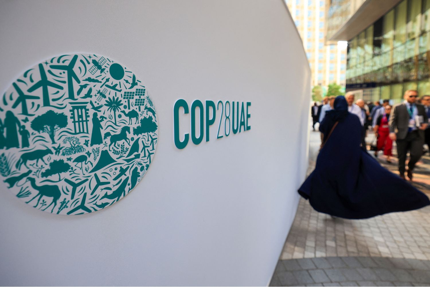 People walk past a COP28 sign at the Expo City during the United Nations climate summit in Dubai on December 5, 2023.