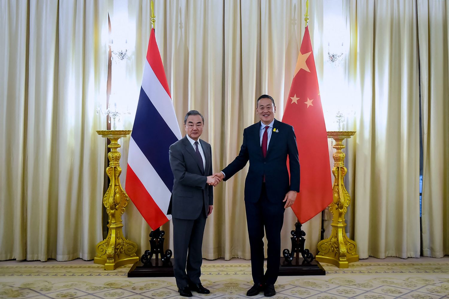 This handout from the Royal Thai Government taken and released on January 29, 2024 shows Thailand's Prime Minister Srettha Thavisin (R) shaking hands with China's Foreign Minister Wang Yi in Bangkok. (Photo by Handout / ROYAL THAI GOVERNMENT / AFP)